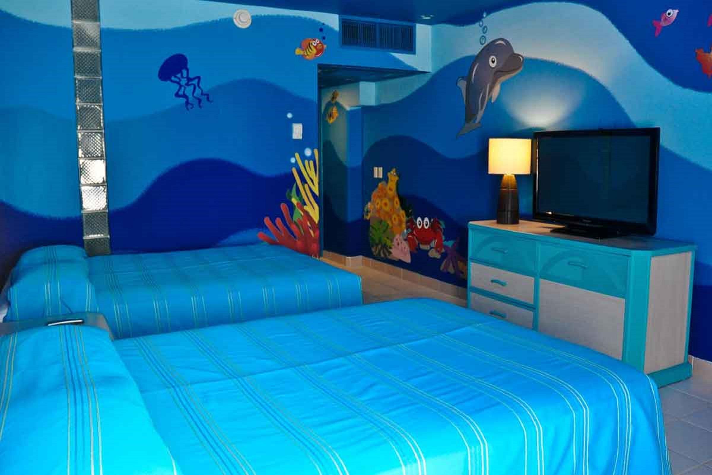 Grand Oasis Palm Hotel Cancún Kültér fotó The photo shows a brightly colored hotel room with a themed underwater design. The walls are painted in various shades of blue, resembling ocean water, and feature colorful sea creatures such as fish and a dolphin. There are two beds with blue stripe